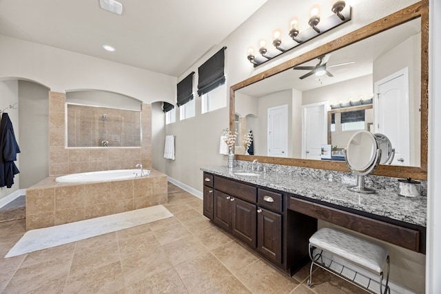 bathroom featuring a ceiling fan, vanity, tiled shower, baseboards, and a bath