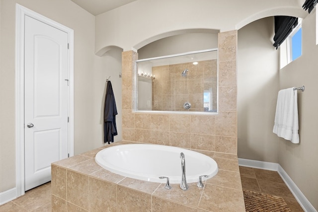 bathroom featuring tile patterned flooring, a tile shower, baseboards, and a bath