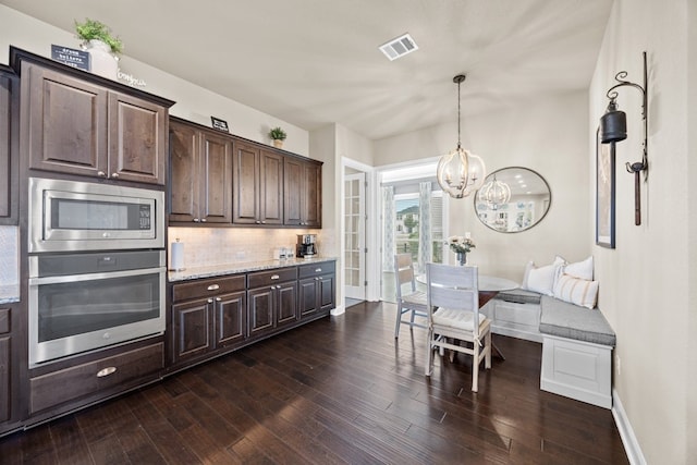 kitchen featuring stainless steel appliances, dark wood finished floors, visible vents, and dark brown cabinetry