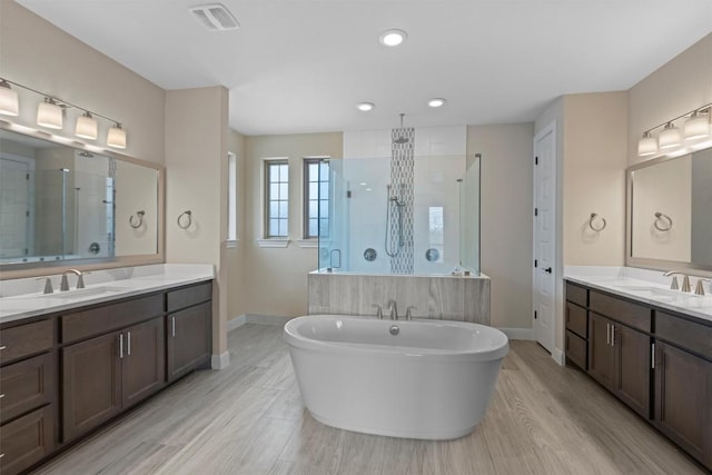 bathroom featuring plus walk in shower, wood-type flooring, and vanity