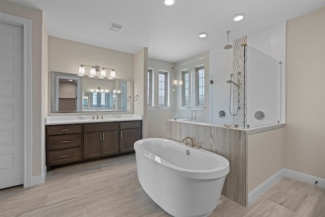 bathroom with hardwood / wood-style flooring, vanity, and shower with separate bathtub