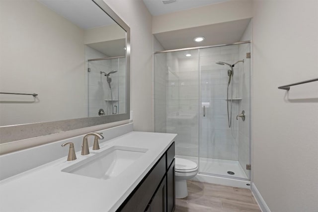 bathroom with hardwood / wood-style flooring, vanity, toilet, and a shower with shower door