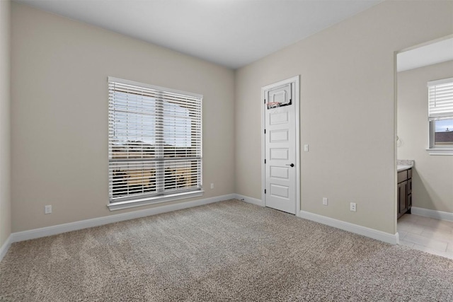 unfurnished bedroom with light colored carpet and ensuite bathroom