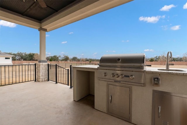 view of patio with ceiling fan, an outdoor kitchen, sink, and grilling area