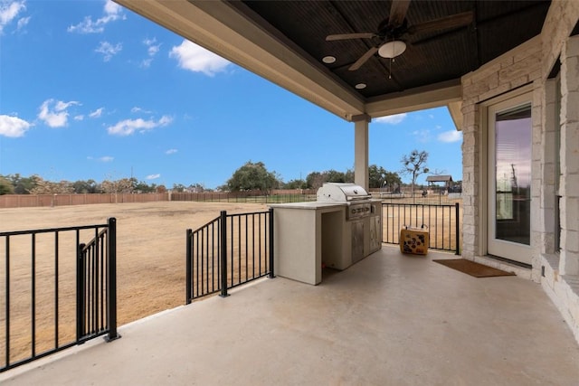 view of patio with an outdoor kitchen, area for grilling, a rural view, and ceiling fan