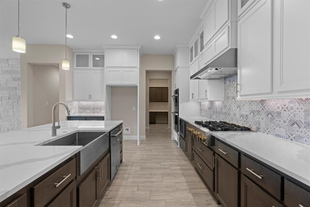 kitchen with sink, white cabinetry, decorative light fixtures, appliances with stainless steel finishes, and decorative backsplash