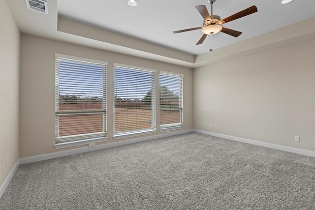 unfurnished room with a raised ceiling, carpet, and ceiling fan