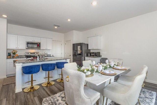 kitchen with stainless steel appliances, white cabinetry, and a center island with sink