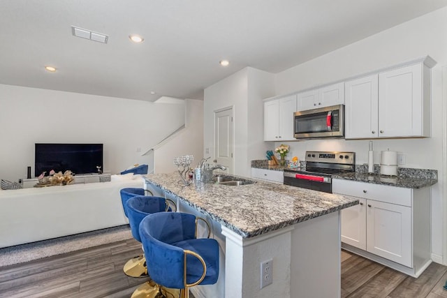 kitchen with stainless steel appliances, a kitchen island with sink, and white cabinets