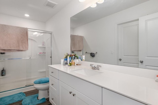 bathroom with vanity, hardwood / wood-style floors, a shower with shower door, and toilet