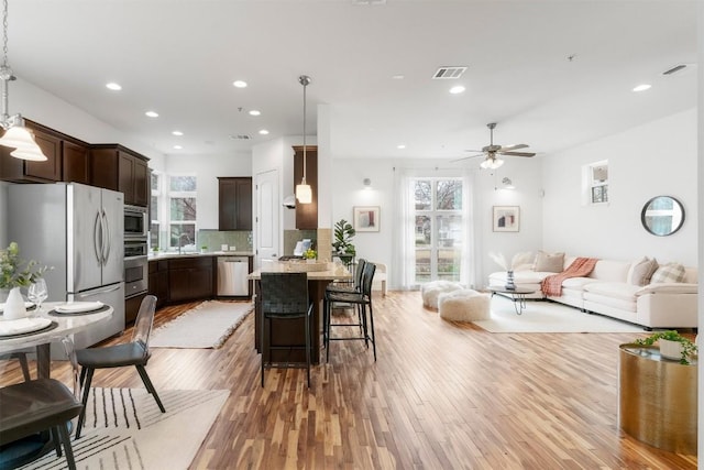 kitchen featuring hardwood / wood-style flooring, stainless steel appliances, decorative light fixtures, and a breakfast bar