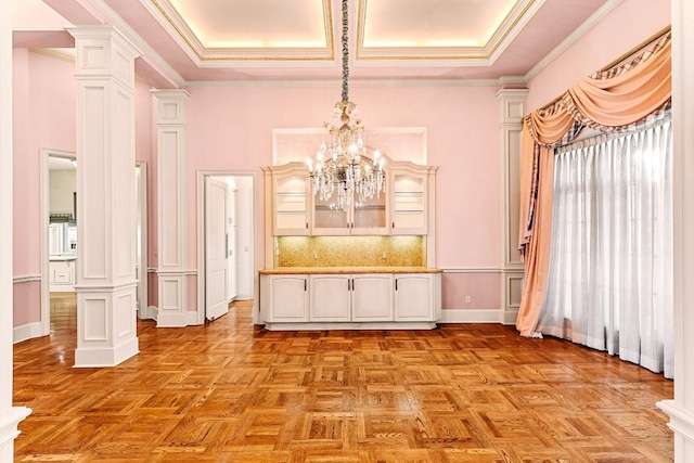 unfurnished dining area with ornamental molding, a chandelier, light parquet floors, and ornate columns