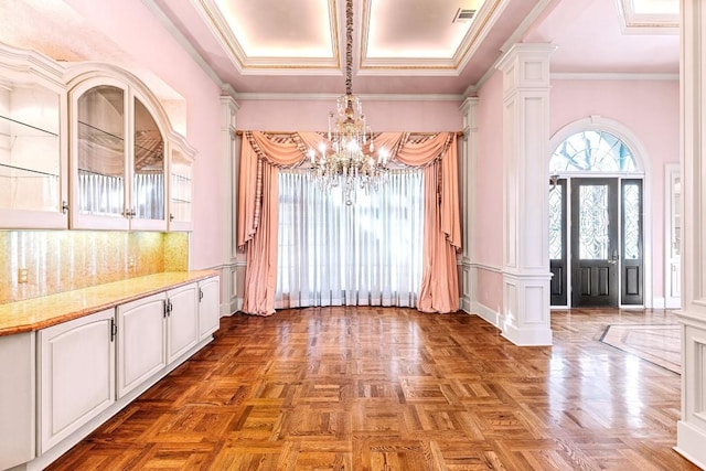 unfurnished dining area featuring decorative columns, dark parquet flooring, crown molding, and a chandelier