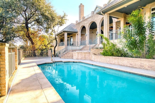 view of swimming pool featuring stairs, a fenced in pool, fence, and a ceiling fan