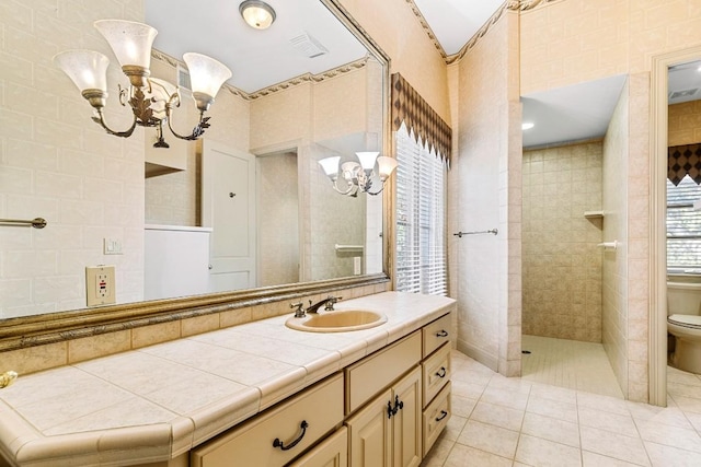 full bath featuring a chandelier, tile walls, tile patterned floors, vanity, and walk in shower