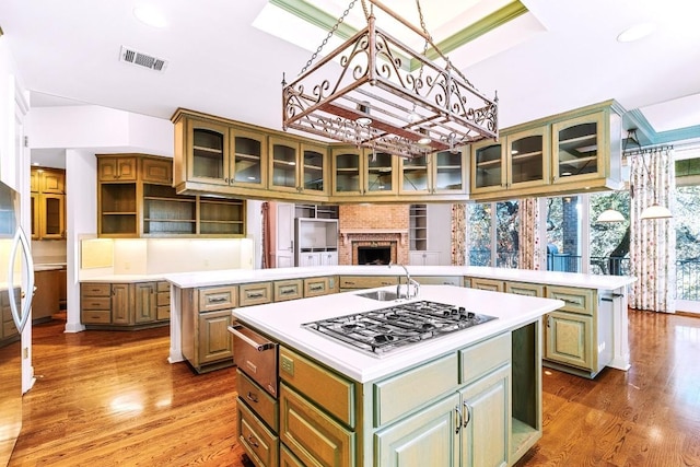 kitchen featuring a center island, stainless steel gas cooktop, wood finished floors, open shelves, and a brick fireplace