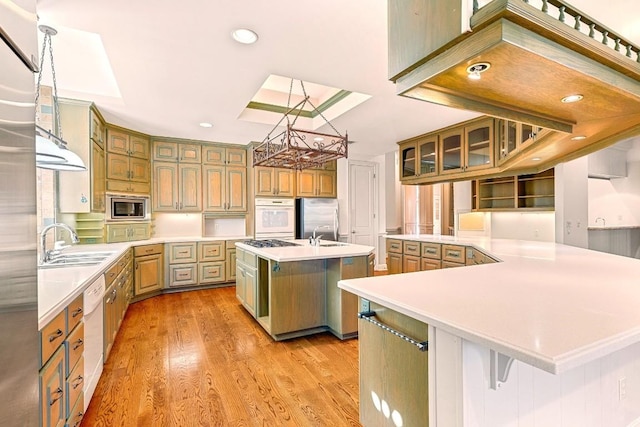kitchen with appliances with stainless steel finishes, a chandelier, a spacious island, light countertops, and light wood-type flooring