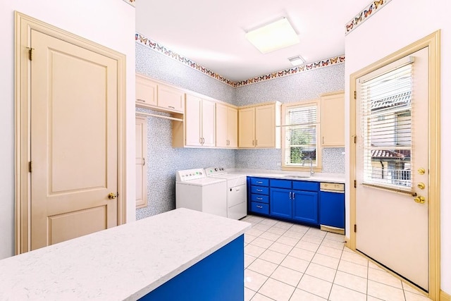 kitchen with dishwashing machine, sink, blue cabinetry, washer and dryer, and light tile patterned flooring