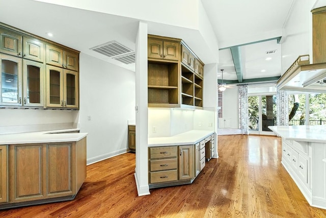 kitchen featuring ceiling fan, dark wood-type flooring, visible vents, light countertops, and glass insert cabinets