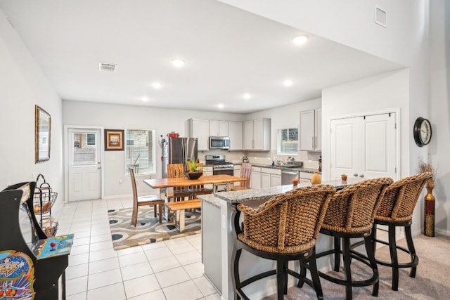 kitchen featuring light tile patterned floors, sink, a breakfast bar, stainless steel appliances, and a center island