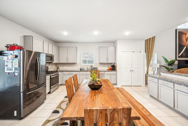 kitchen featuring light tile patterned flooring, appliances with stainless steel finishes, tasteful backsplash, sink, and light stone counters