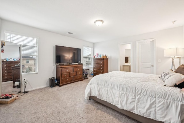 bedroom featuring light colored carpet and ensuite bathroom