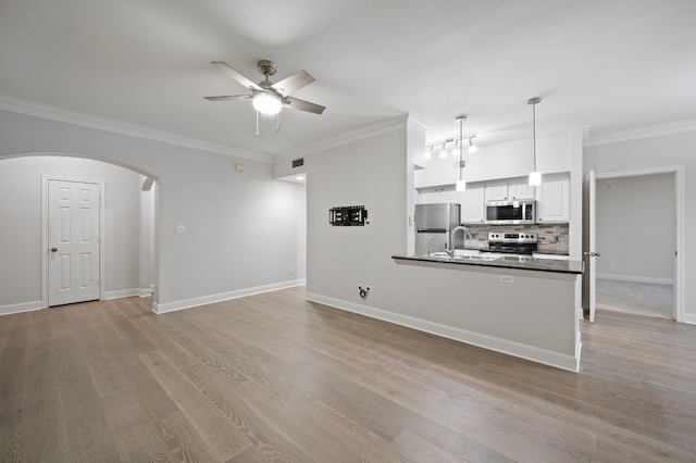 unfurnished living room featuring ornamental molding, ceiling fan, and light hardwood / wood-style flooring