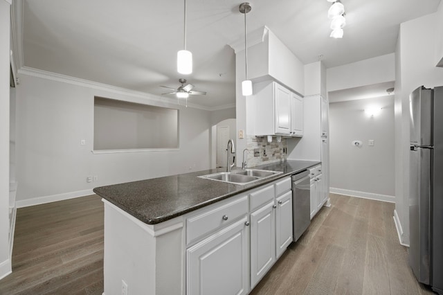 kitchen with hardwood / wood-style floors, white cabinetry, sink, hanging light fixtures, and stainless steel appliances