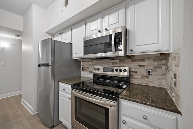 kitchen featuring tasteful backsplash, light hardwood / wood-style flooring, dark stone countertops, stainless steel appliances, and white cabinets