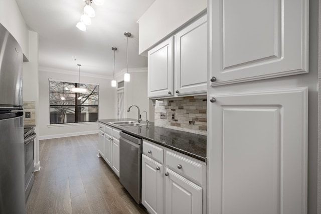 kitchen with appliances with stainless steel finishes, sink, white cabinets, decorative backsplash, and hanging light fixtures