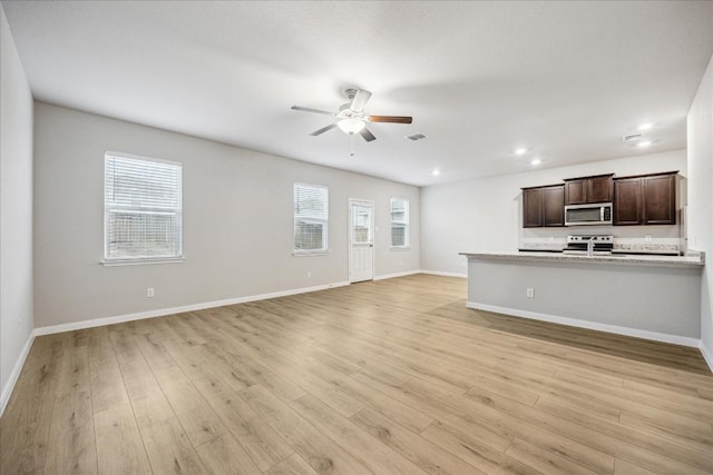 unfurnished living room featuring ceiling fan, a healthy amount of sunlight, and light wood-type flooring