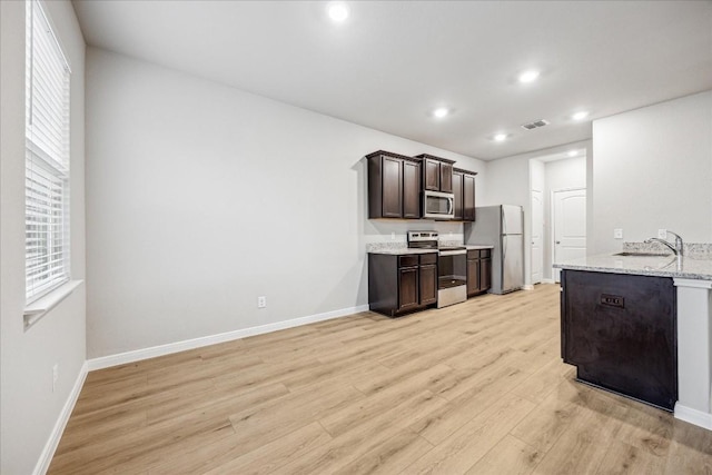 kitchen with sink, light hardwood / wood-style flooring, dark brown cabinets, stainless steel appliances, and light stone countertops