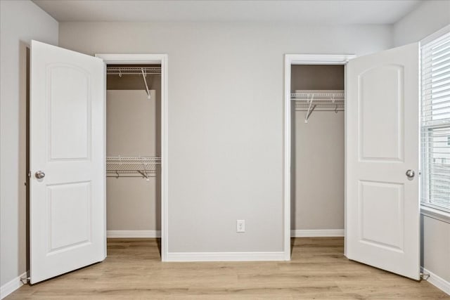 unfurnished bedroom featuring light hardwood / wood-style flooring and two closets