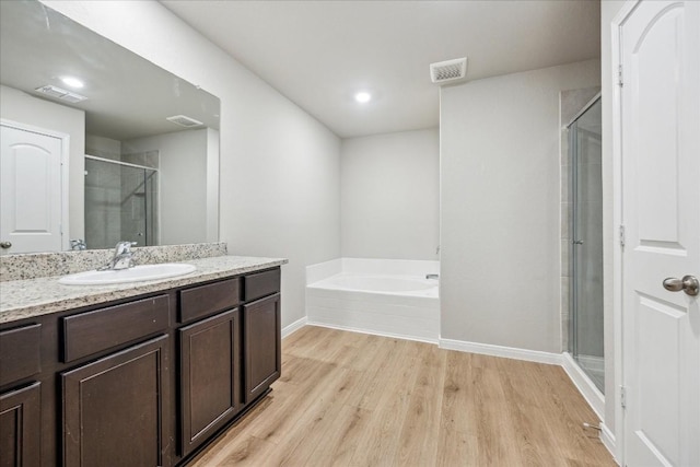 bathroom featuring hardwood / wood-style flooring, vanity, and shower with separate bathtub