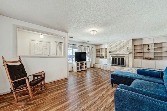 living room featuring hardwood / wood-style floors, a textured ceiling, and a brick fireplace