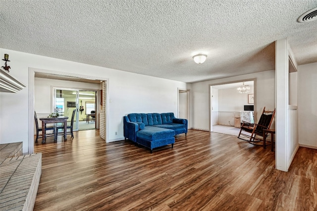 living area featuring an inviting chandelier, dark hardwood / wood-style floors, and a textured ceiling