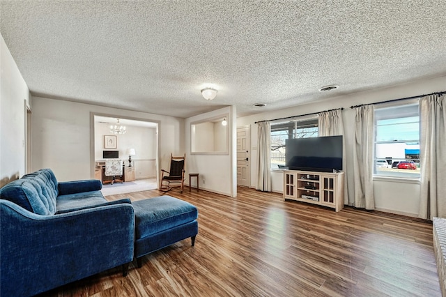 living room featuring a notable chandelier, wood-type flooring, and a textured ceiling