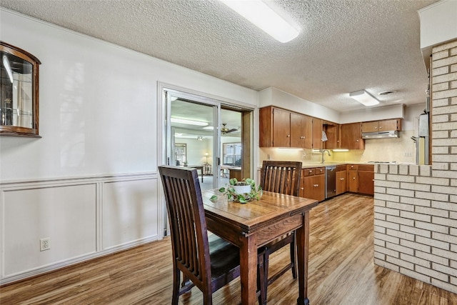 dining room with ceiling fan, sink, a textured ceiling, and light wood-type flooring