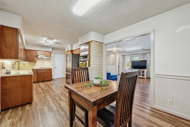 dining space featuring sink, a textured ceiling, and light hardwood / wood-style floors