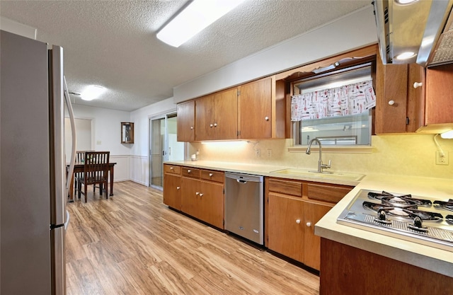 kitchen featuring sink, stainless steel appliances, light hardwood / wood-style floors, and a textured ceiling