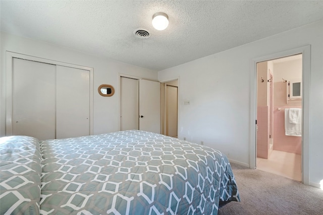 carpeted bedroom with multiple closets, ensuite bathroom, and a textured ceiling