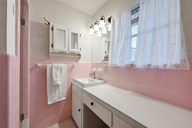 bathroom with tile walls, vanity, tile patterned floors, and a textured ceiling