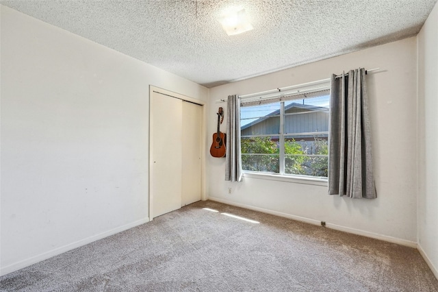 spare room featuring light colored carpet and a textured ceiling