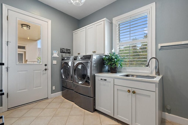 clothes washing area with cabinets, sink, light tile patterned floors, and independent washer and dryer