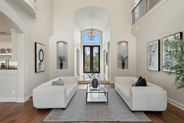 living room featuring french doors, a notable chandelier, dark hardwood / wood-style floors, and a high ceiling