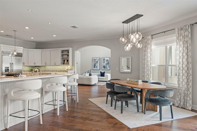 dining space with ornamental molding, dark hardwood / wood-style floors, and sink