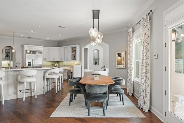 dining area with crown molding, dark hardwood / wood-style floors, and sink