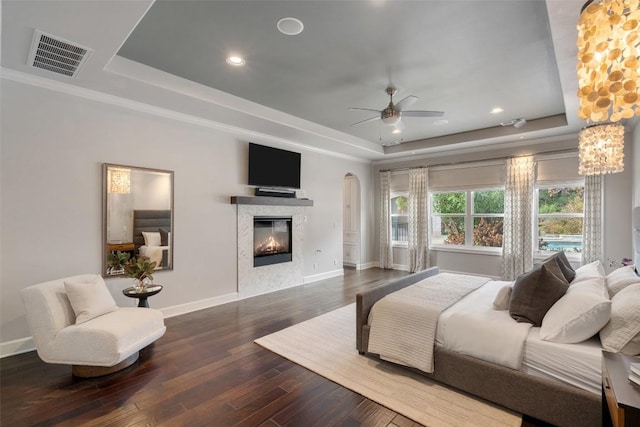 bedroom with hardwood / wood-style floors, a tray ceiling, and ceiling fan