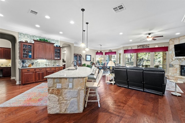 804 Laughing Dog Ct, Leander, TX 78641 - kitchen featuring arched walkways, ceiling fan, open floor plan, crown molding, and a kitchen bar