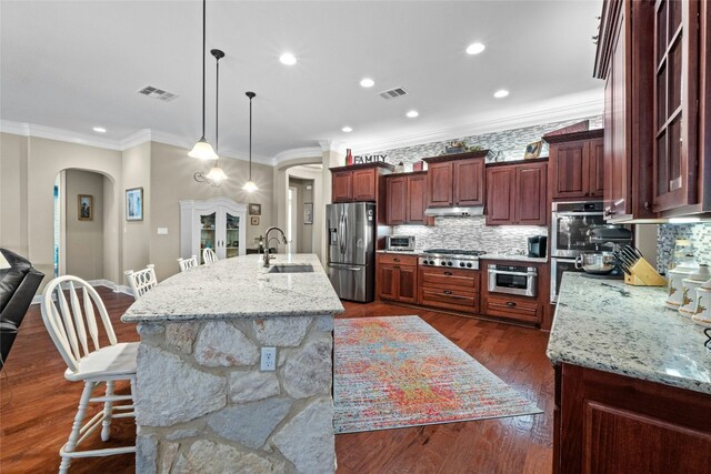 804 Laughing Dog Ct, Leander, TX 78641 - kitchen with arched walkways, appliances with stainless steel finishes, crown molding, a breakfast bar area, and decorative backsplash
